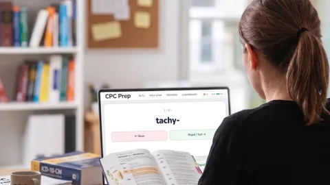 Medical coder reviewing CPT modifier codes at a clinic computer